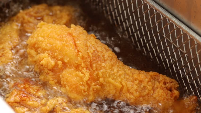 Deep fry chicken drumstick in deep fryer. frying in hot boiling oil. Close up shot