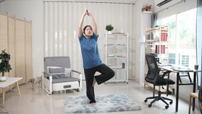 Active and healthy Asian girl with a fit body is exercising at home, lifting dumbbells, doing yoga, stretching on a yoga mat and exercising. Healthy lifestyle, peace