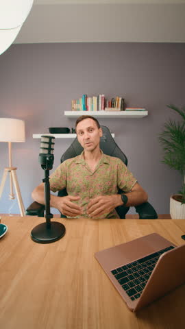 A man records a podcast at home with a laptop and microphone, showing a professional setup