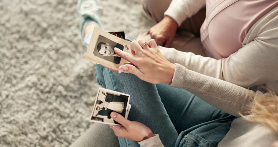 Hands, people or photograph for memory in home for nostalgia, learning or to remember. Parent, mom or family with pictures of old monochrome, ancient history or retro album on carpet in house lounge