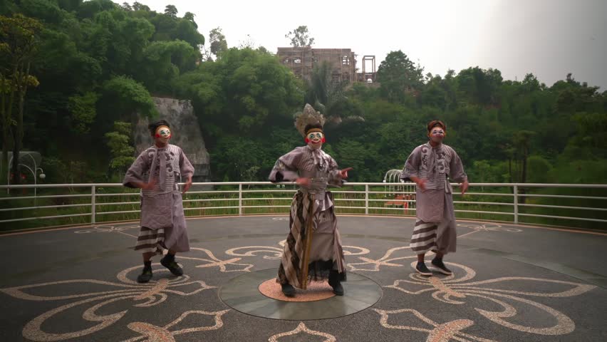Three performers in traditional Japanese attire and masks engage in a cultural dance outdoors, with lush greenery and a historic building in the background.