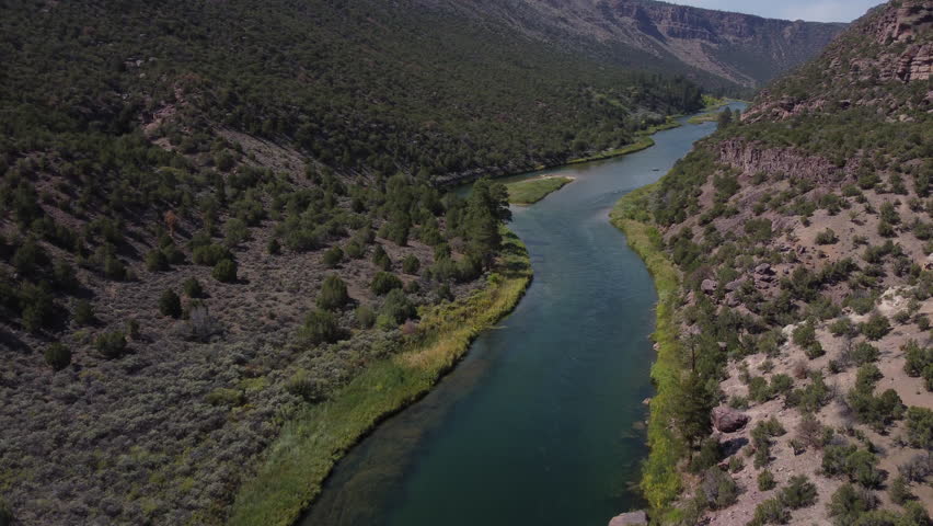 Forward moving and rotating aerial view of Green River in Utah in the fall with fishing boat.
