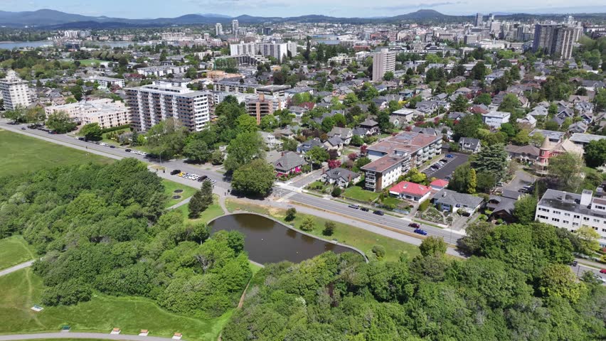 aerial forward flight from Pacific Ocean northbound across James Bay District, Victoria, BC toward Victoria Inner Harbor with Downtown and other districts in background. aerial Video Footage 