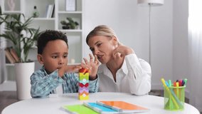 Assessment of mental development of children. Professional psychologist observes small multiracial boy playing with puzzle game, assessing his readiness for preschool. Exercises for kid with autism. - Powered by Shutterstock - Get 15% off with code: PIKWIZARD15