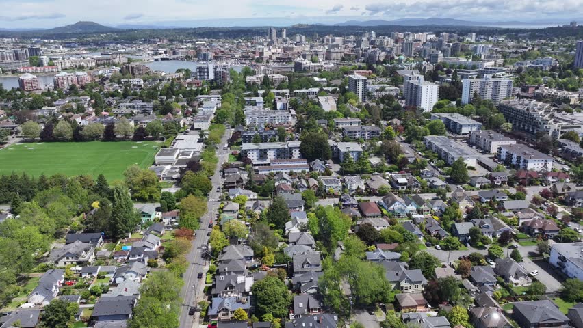 aerial forward flight from Pacific Ocean across James Bay District, Victoria, BC toward Victoria Inner Harbor with Downtown and other districts in background. aerial Video Footage 