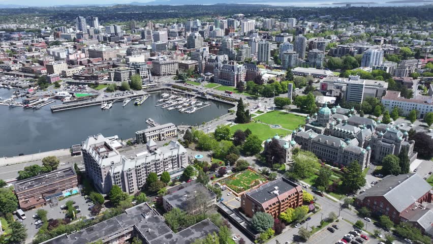 hovering above James Bay district, left panning across Victoria Inner Harbor till Ogden Point Pier, with Downtown Victoria and other districts in background, aerial video footage Vancouver Island, BC 