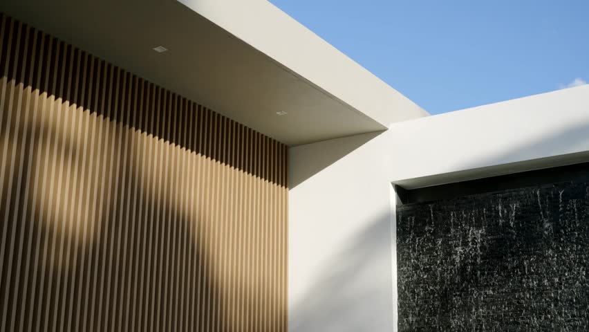 Contemporary architectural detail featuring contrast between textures and materials. Vertical wooden slat wall with warm tone and section of dark structure with running water