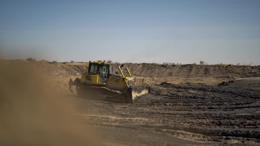 Bulldozer moves pile of soil creating smooth surface for building site. Equipment easily pushes ground preparing area for installing pipelines