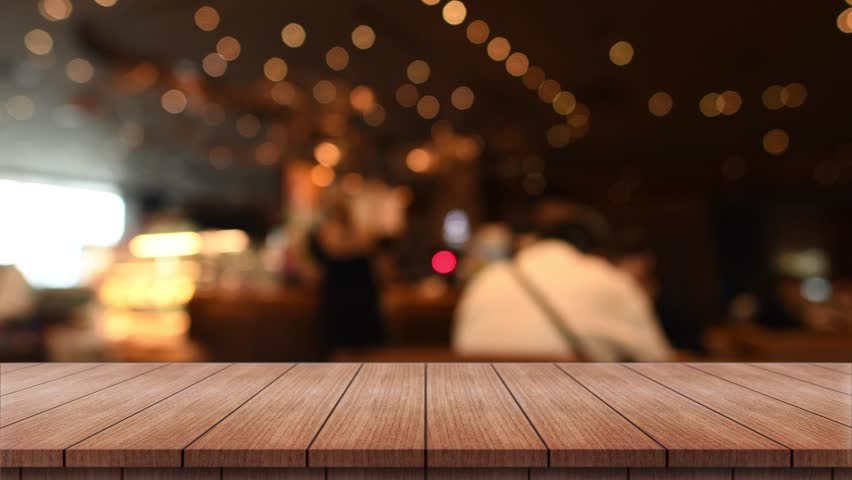 Empty wooden table top with lights bokeh on blur restaurant background.