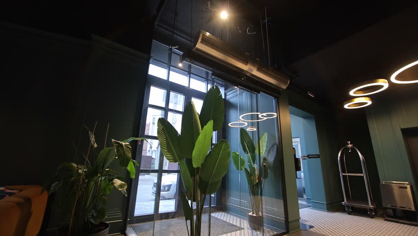 Modern hotel lobby entrance, A stylish hotel lobby entrance with large glass doors and indoor plants, showcasing contemporary interior design and welcoming atmosphere.