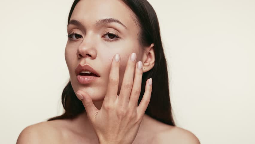 Close-up of a person applying cream on their skin, focusing on skincare and beauty, isolated on a light background.