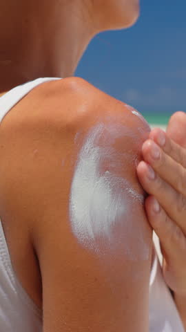 Vertical video. Close-up beauty woman applies sun cream on on the shoulder enjoys the sun