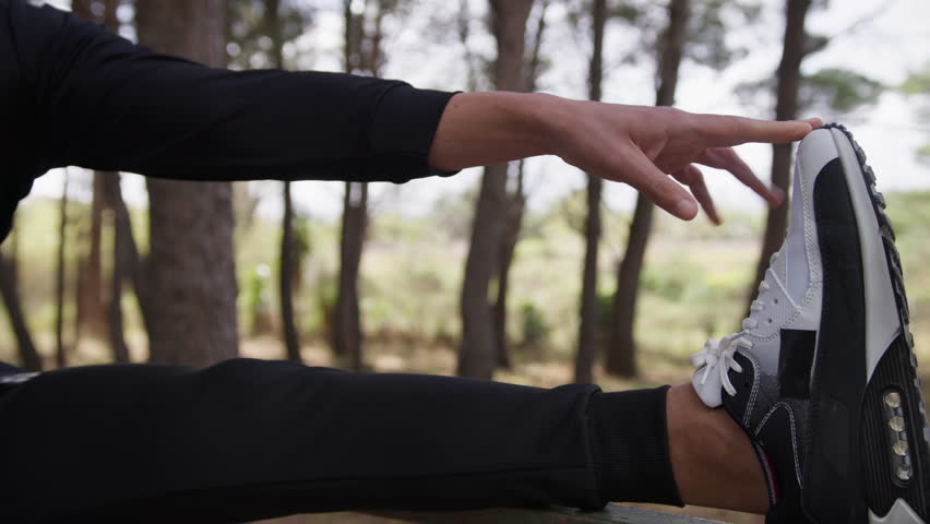Hand Of A Man Dressed In Black Does Stretching With His Leg On The Tree