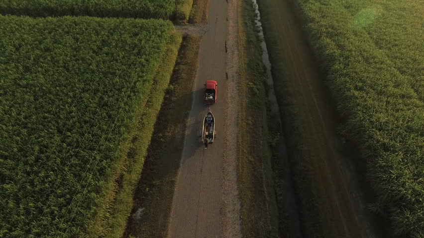 Aerial: Drone Forward Shot Of Pick-Up Vehicle Pulling Boat Moving On Road In Agricultural Field - Bayou Vista, Texas