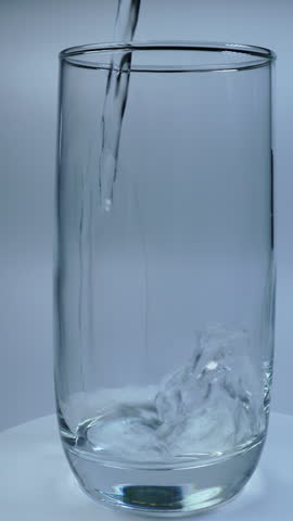 Vertical view of pouring mineral water into glass, air bubble.