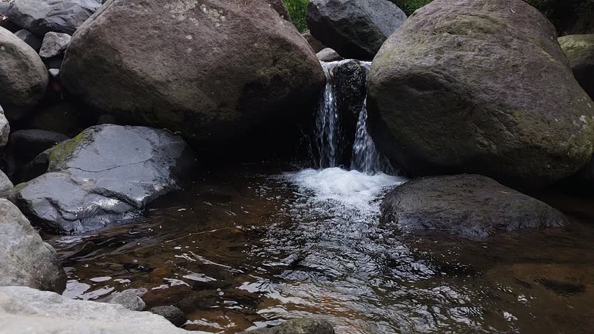 Clear water flows from the mountains to form small waterfalls between the rocks 01