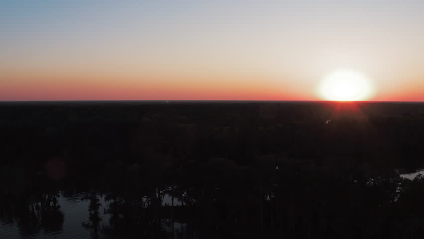 Aerial Panning Beautiful Shot Of River In Tranquil Forest, Drone Flying Over Dark Trees In Forest Against Orange Sky At Sunset - Bayou Vista, Texas