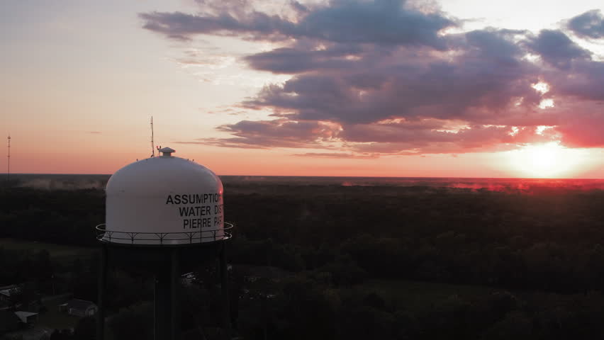 Aerial Backward Panning Scenic Shot Of Tall Water Storage Tank In Forest During Sunset - Bayou Vista, Texas