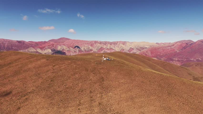 Aerial rising shot revealing the Cerro de los 14 colores from behind a mountain