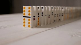 Stacked white dominoes falling over. Dominoes falling down isolated on white background. White domino dice with multicolored dots fall on a light wooden background, the background is blurred. - Powered by Shutterstock - Get 15% off with code: PIKWIZARD15