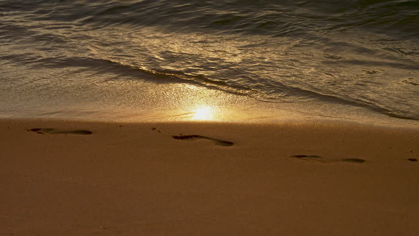 Sea Waves Washing Off Human Footprints in the Seashore Sand. The Concept of the Frailty of Human Existence