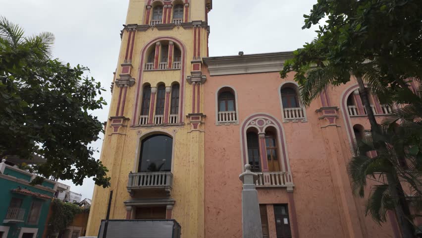Historic university building in Cartagena, Colombia with a pink facade and palm trees in view