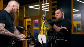 In a motorcycle repair shop a mechanic ties a motorbike to an overhead lift - Powered by Shutterstock - Get 15% off with code: PIKWIZARD15