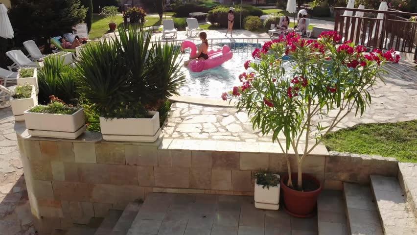 Aerial drone view of woman on pink flamingo pool float in pool in hotel. Summer holidays, enjoying summer vacations footage from above
