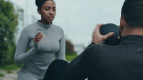 Focused couple engaging in partner workout using a medicine ball for a Russian twist exercise in an outdoor setting. - Powered by Shutterstock - Get 15% off with code: PIKWIZARD15