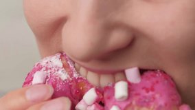 A closeup picture showing a person delighting in a pink donut with colorful sprinkles - Powered by Shutterstock - Get 15% off with code: PIKWIZARD15