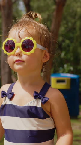 Vertical video. The little girl is resting in sunglasses