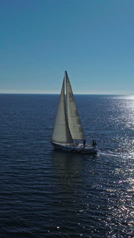 VERTICAL VIDEO. Aerial view of yacht sailing on opened sea. Sailing boat. Yacht from drone. Yachting video. Yacht from above. Sailboat from drone. Sailing video. Yachting at windy day