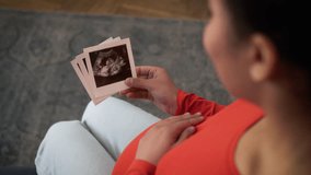 Pregnant African American woman girl female mother enjoying pregnancy at home couch sofa hold unborn baby photo ultrasound pictures touching stroking belly anticipation child medicine medical test - Powered by Shutterstock - Get 15% off with code: PIKWIZARD15