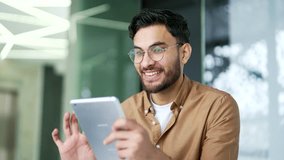 Happy businessman is using digital tablet sitting at workplace in business office. Smiling man worker works on application, reading typing a message, chatting online or browsing social media Close up - Powered by Shutterstock - Get 15% off with code: PIKWIZARD15