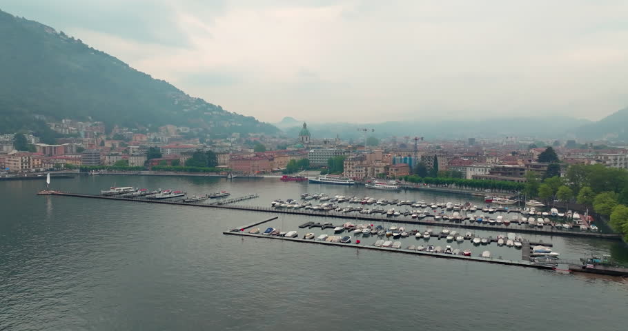 Aerial view of the landscape of the lake and the city of Como in Italy. Marina with moored boats in the port, cityscape of the streets of the city in the Alps. High quality 4k footage