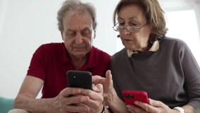 Elderly couple using smartphones together, sitting closely on a couch, both focused on their screens, showcasing technology use among seniors, collaboration, and modern communication in a home setting - Powered by Shutterstock - Get 15% off with code: PIKWIZARD15
