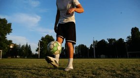 Professional footballer juggling soccer ball on stadium at sunset. Young man kicking ball at green field. Sportsman practicing tricks at meadow with sunlight at background. Freestyle football concept - Powered by Shutterstock - Get 15% off with code: PIKWIZARD15