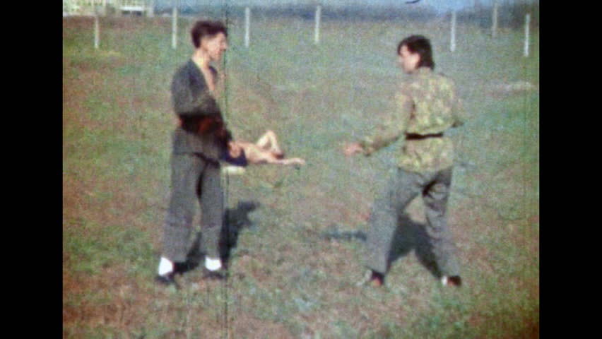Epic combat technique of Asian martial arts. Practice of disarming protective karate technique. Male karateka repealing sparring partner, opponent attack. Vintage color film. Retro 1980s archive