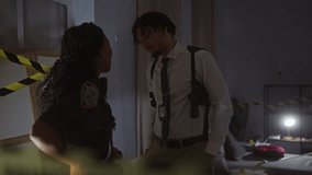 A woman officer and a man investigator converse seriously in a dimly lit indoor crime scene. - Powered by Shutterstock - Get 15% off with code: PIKWIZARD15