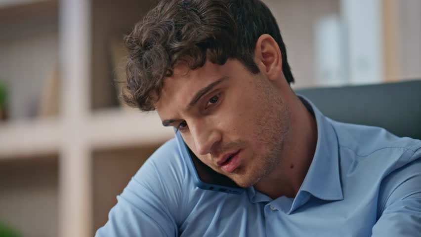 Young professional answering mobile phone call closeup. Busy sales manager talk consulting client on smartphone conversation. Handsome brunette businessman working office discussing project in agency