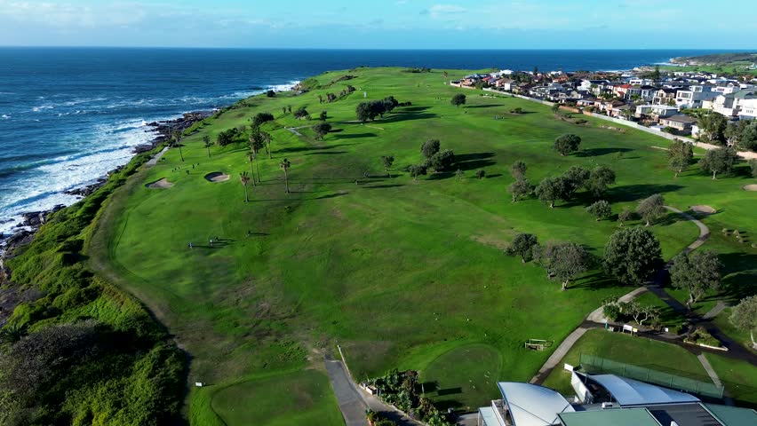 Landscape pan of trees on Randwick Malabar Golf course greens fairway by coastline oceanside sea waves headland Sydney Australia drone aerial