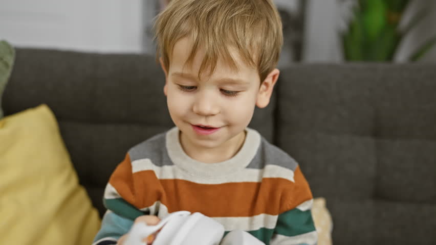 A blonde toddler boy plays with a toy in a cozy living room, exemplifying innocence and childhood.