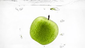 Green apple is falling into clear water filmed in slow motion on white background. Fresh fruit is plunging into transparent aqua and swimming. Closeup view of delicious and juicy vegetarian food - Powered by Shutterstock - Get 15% off with code: PIKWIZARD15