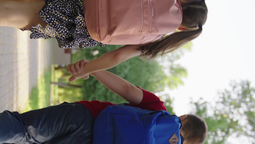 boy girl holding hands running through park school, child with school backpacks running along sidewalk school lesson, cheerful classmates running hand hand with bags, teamwork group children, boy girl