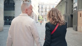 Back view of a middle aged married couple holding hands while smiling and looking at camera. Mature husband and wife having a good time on a romantic trip in Europe. Happy mid adult mates enjoying - Powered by Shutterstock - Get 15% off with code: PIKWIZARD15