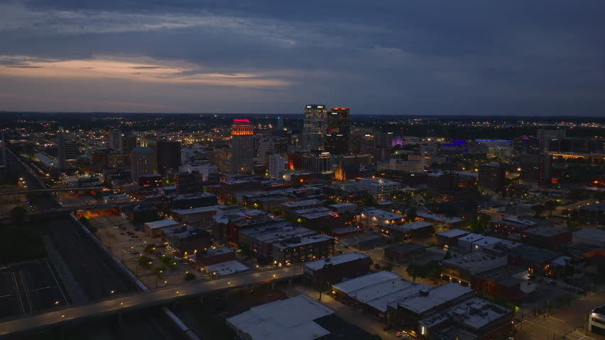 Aerial view of Birmingham, USA at dusk, showcasing the illuminated cityscape under a twilight sky. Urban, travel, and real estate themes in a medium sized American city