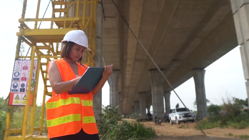 Civil engineer inspects tollway bridge structure,Contractors check specifications before delivering work.