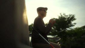 The young blind man using voice control app on smartphone while sitting on a bench against beautiful sunlight in the city park, disabled visually impaired man talking on cellphone for communication.
 - Powered by Shutterstock - Get 15% off with code: PIKWIZARD15