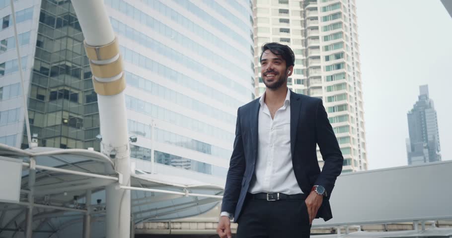 Successful negotiations completed, businessman in formal suit satisfaction. Wide smile and victorious gesture indicate successful. City financial district in background highlights successful deal.
