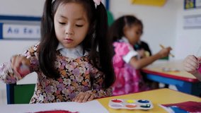 Asian kid girl painting during art class in kindergarten class room. Multiracial children students and school education - Powered by Shutterstock - Get 15% off with code: PIKWIZARD15